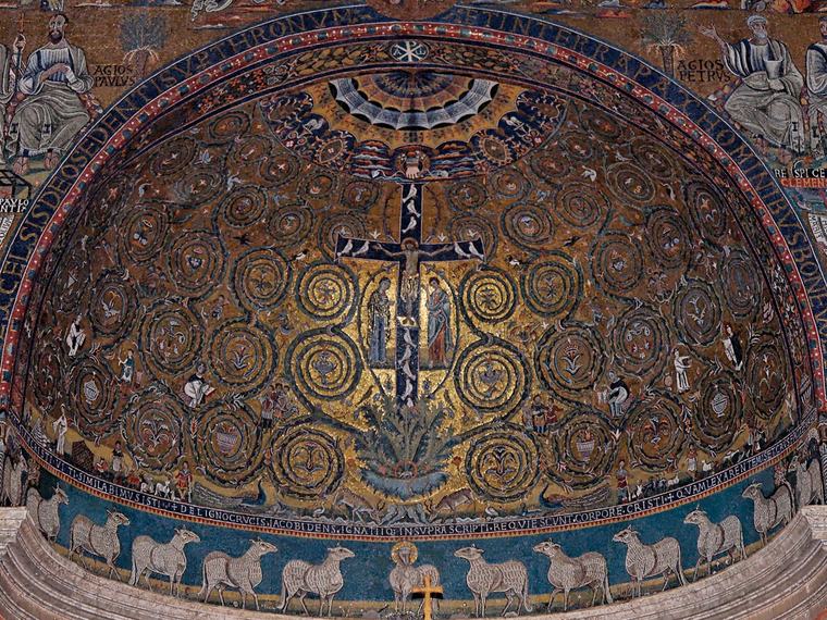 Golden half-dome mosaic showing a dark cross with the crucified Christ rising from an acanthus plant, surrounded by spiraling green and gold vine scrolls, above a blue frieze of white lambs.