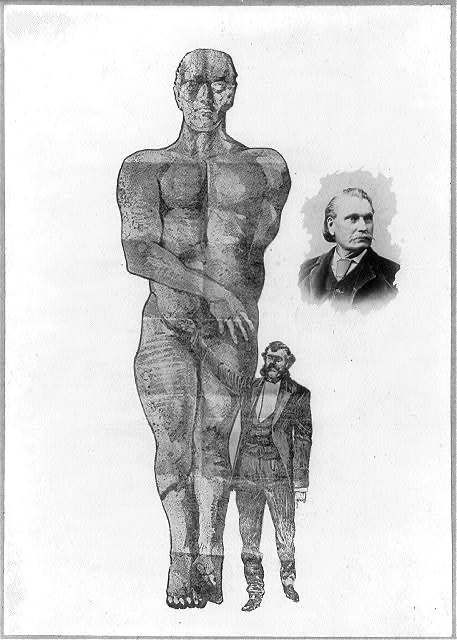 Ein Mann sitzt neben der großen geschnitzten Figur des Cardiff Giant.