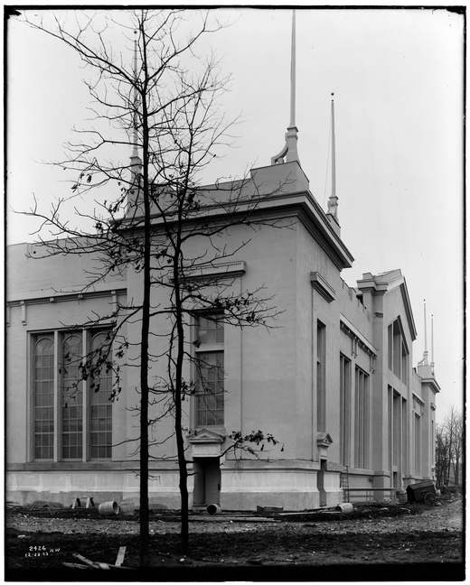 Schwarz-Weiß-Foto der Ecke eines großen Ausstellungsgebäudes, das aus schlammigem, unbepflanztem Boden aufragt.
