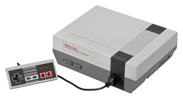 A gray Nintendo Entertainment System console with a rectangular controller connected by a black cable, on a white background.