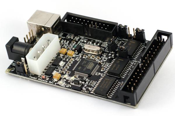 A black circuit board with a USB port, a white power connector, a central microchip and two long ribbon-cable pin headers, photographed at an angle against a white background.