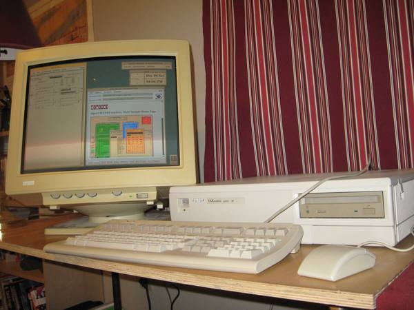 A cream-colored desktop workstation with a CRT monitor, keyboard and mouse on a wooden desk in front of a red-striped curtain. The screen shows several windows, including one titled NCSA Mosaic Document View.