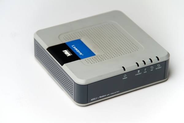 A light gray Linksys ADSL2+ modem with a dark gray front panel, a blue and black Linksys and Cisco Systems label on top and a row of status lights, photographed on a white background.