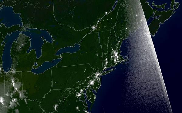 A dark satellite map of the northeastern United States and eastern Canada at night, with state borders outlined in white and only a few clusters of lights visible, mainly in New England, along the Mid-Atlantic seaboard and around Montreal.