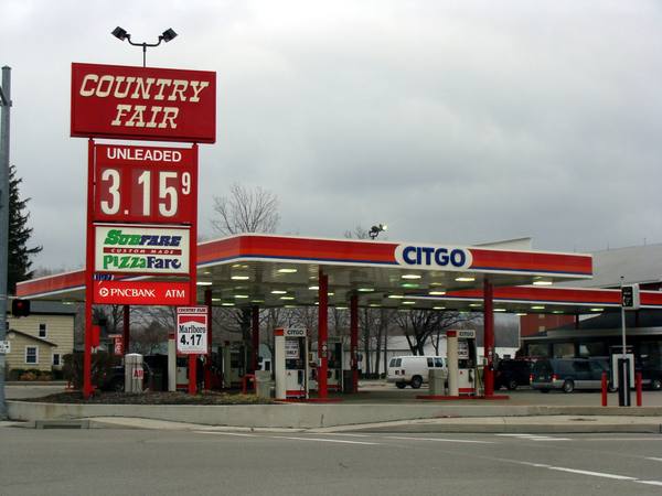 A gas station with a tall red Country Fair sign showing Unleaded 3.15 with a raised 9, a Citgo canopy and fuel pumps under an overcast sky.
